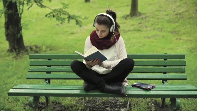 girl-listening-music-and-reading-book-in-the-park_nksvli4p__F0000