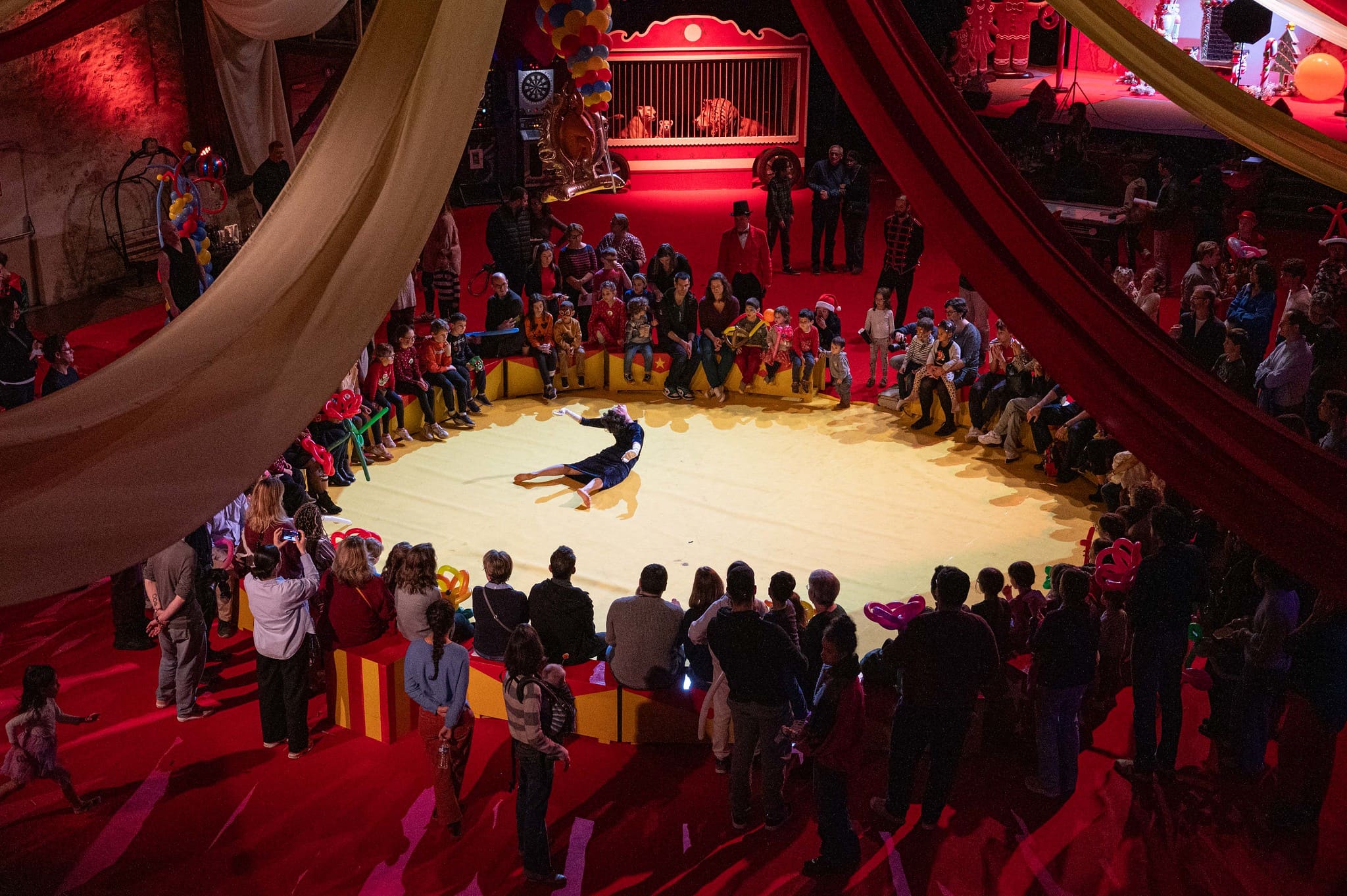 Scénographie immersive arbre de Noël CSE - ambiance lumineuse rouge et décors de cirque pour 450 participants