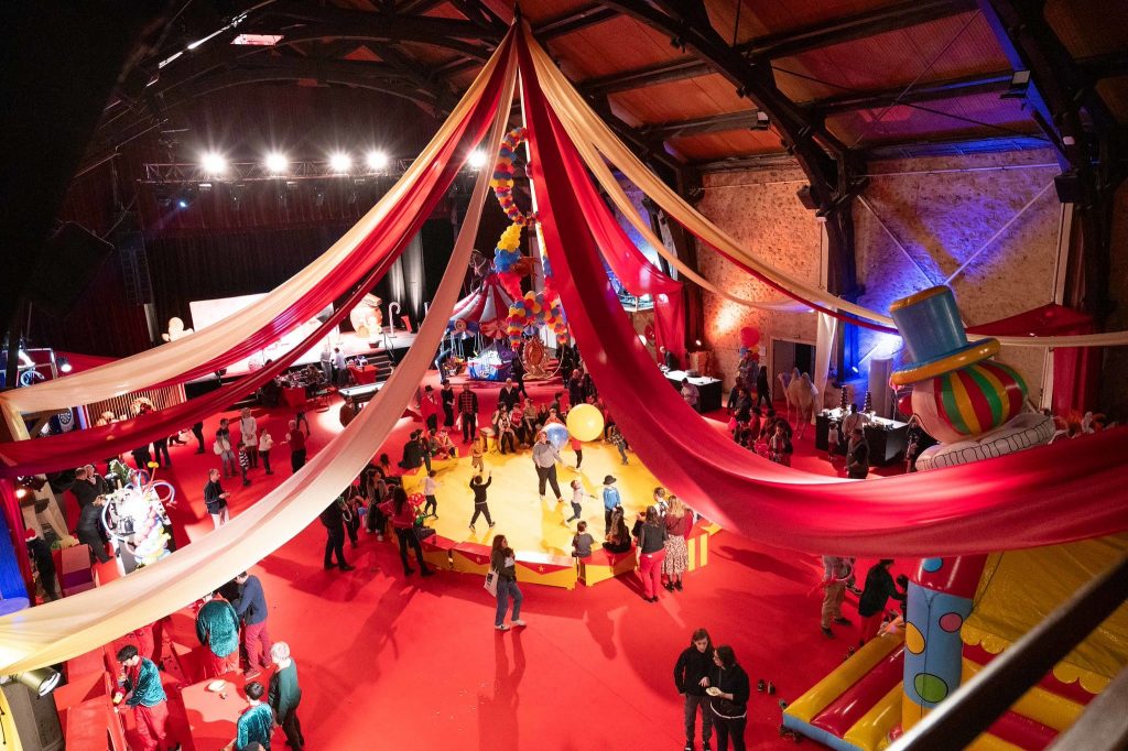Arbre de Noël CSE thème cirque - salle transformée en chapiteau avec drapés rouges et jaunes par Belle Aventure Production