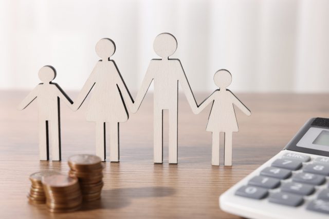 Alimony. Figures of family, coins and calculator on wooden table, closeup Aides de la CAF pour les familles à la rentrée scolaire