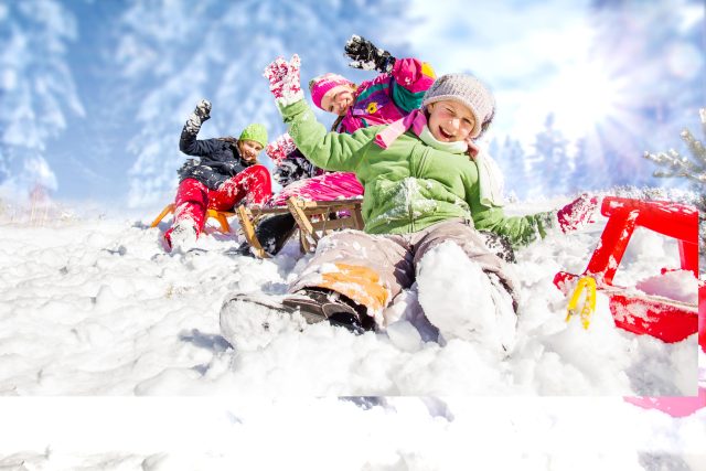 Vacances d’hiver des grandes familles- CSE : enfants en combinaison de ski jouant dans la neige pendant les vacances d’hiver